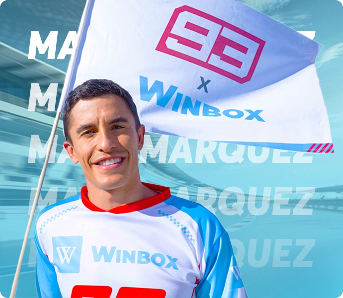 Marc Marquez holding the Winbox partnership flag while wearing the official Winbox jersey